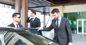 A person getting into a car, protected by security personnel