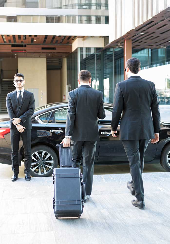 A man approaching a car, protected by security personnel